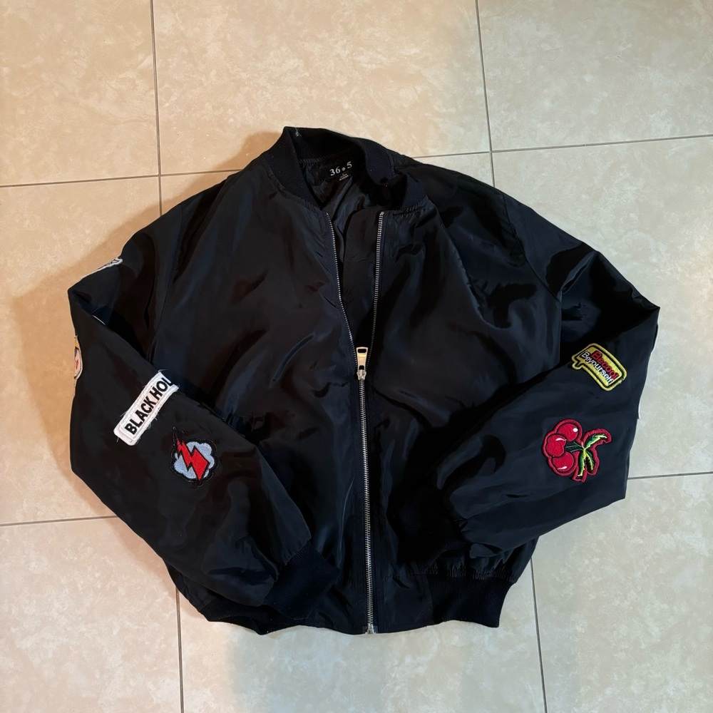 Black bomber jacket with zipper closure and patchwork. In great condition